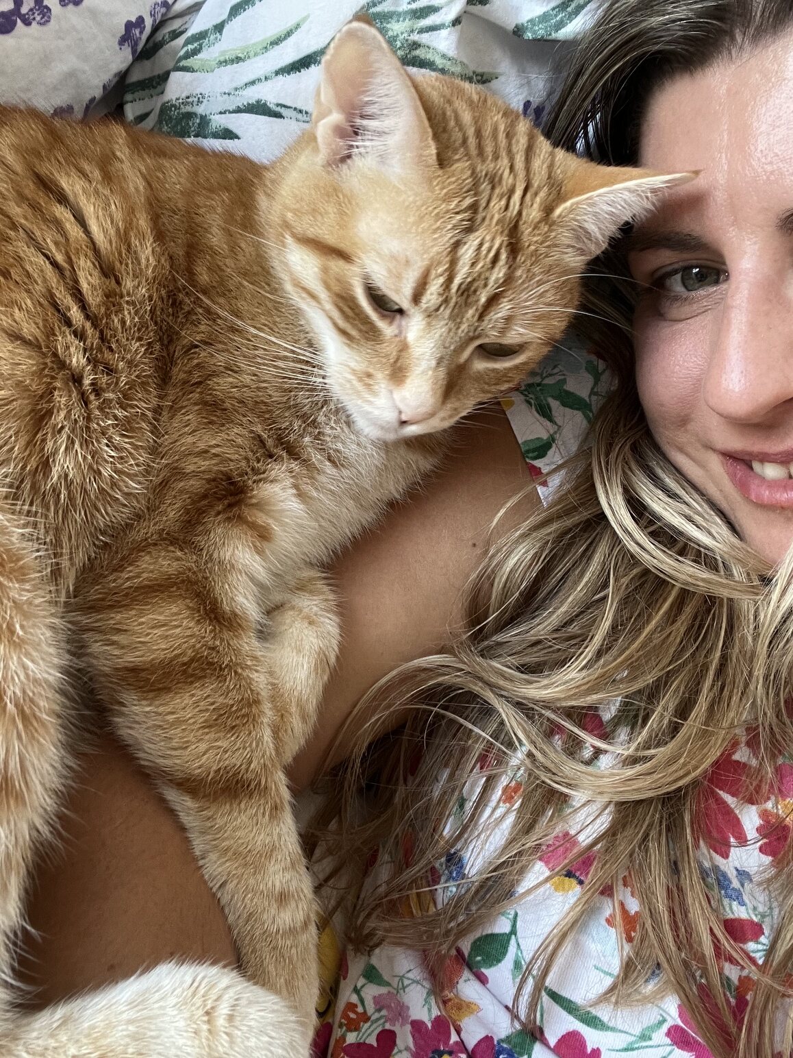 Aneta odpočívá se zrzavou kočkou stočenou na hrudi